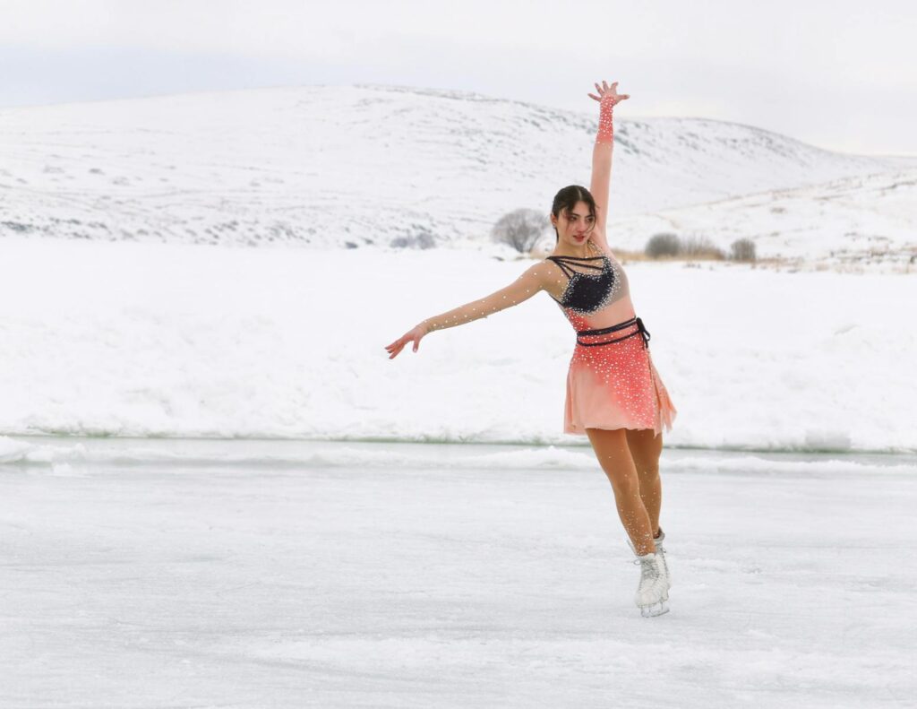 Elegant figure skater performing on a frozen lake with snowy hills in the backdrop in Arpaçay, Kars, Türkiye.