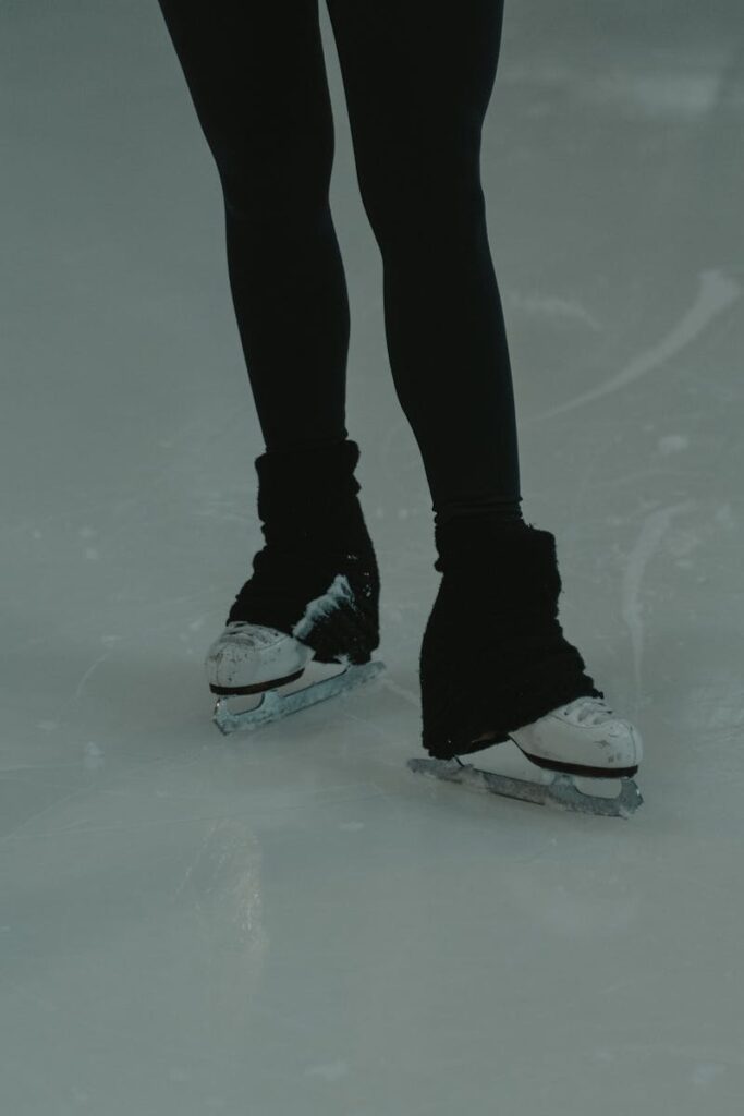 A detailed view of an ice skater's feet gliding on the rink indoors.