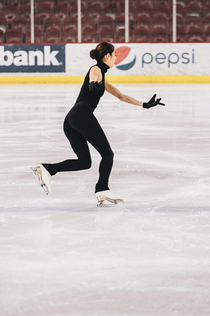 woman in black tank top and black pants doing ice skating